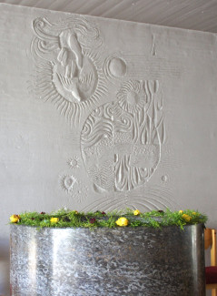 Taufstein mit Relief und Blumenschmuck