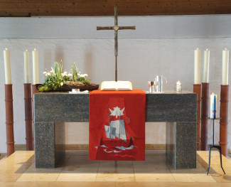 Altar mit rotem Antependium, Kreuz und Kerzen