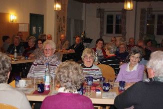 Seniorinnen und Senioren an gedeckten Tischen