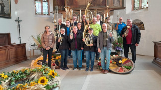 Der Posaunenchor mit Instrumenten in der Kirche, davor Erntedankschmuck