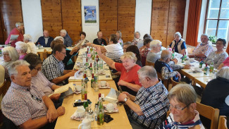 Seniorinnen und Senioren an gedeckten Tischen im Gemeindesaal