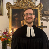 Porträt von Vikar Paul Frohmann im Talar vor einem Altar